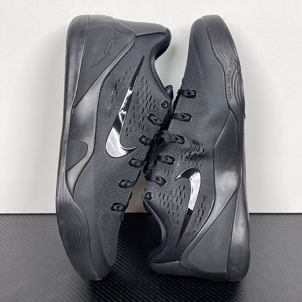 Side profile of the Nike Kobe 9 EM Low Protro TB sneaker in a monochromatic 'Triple Black' colorway, showcasing the stealthy Engineered Mesh upper, tonal black Swoosh, carbon fiber heel counter, and the signature black pressure-mapped outsole.