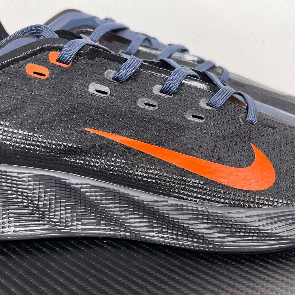 Side profile of the Nike Ava X sneaker in the 'Dark Obsidian Bright Mandarin' colorway, showcasing a deep navy blue breathable mesh upper, vibrant orange contrasting Swoosh and synthetic overlays, and a sculpted, responsive foam midsole.