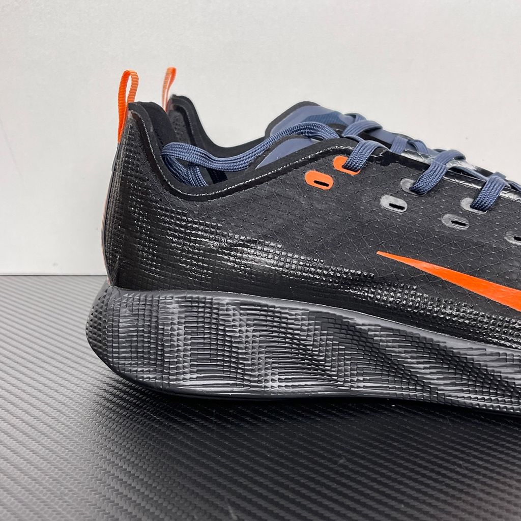 Side profile of the Nike Ava X sneaker in the 'Dark Obsidian Bright Mandarin' colorway, showcasing a deep navy blue breathable mesh upper, vibrant orange contrasting Swoosh and synthetic overlays, and a sculpted, responsive foam midsole.