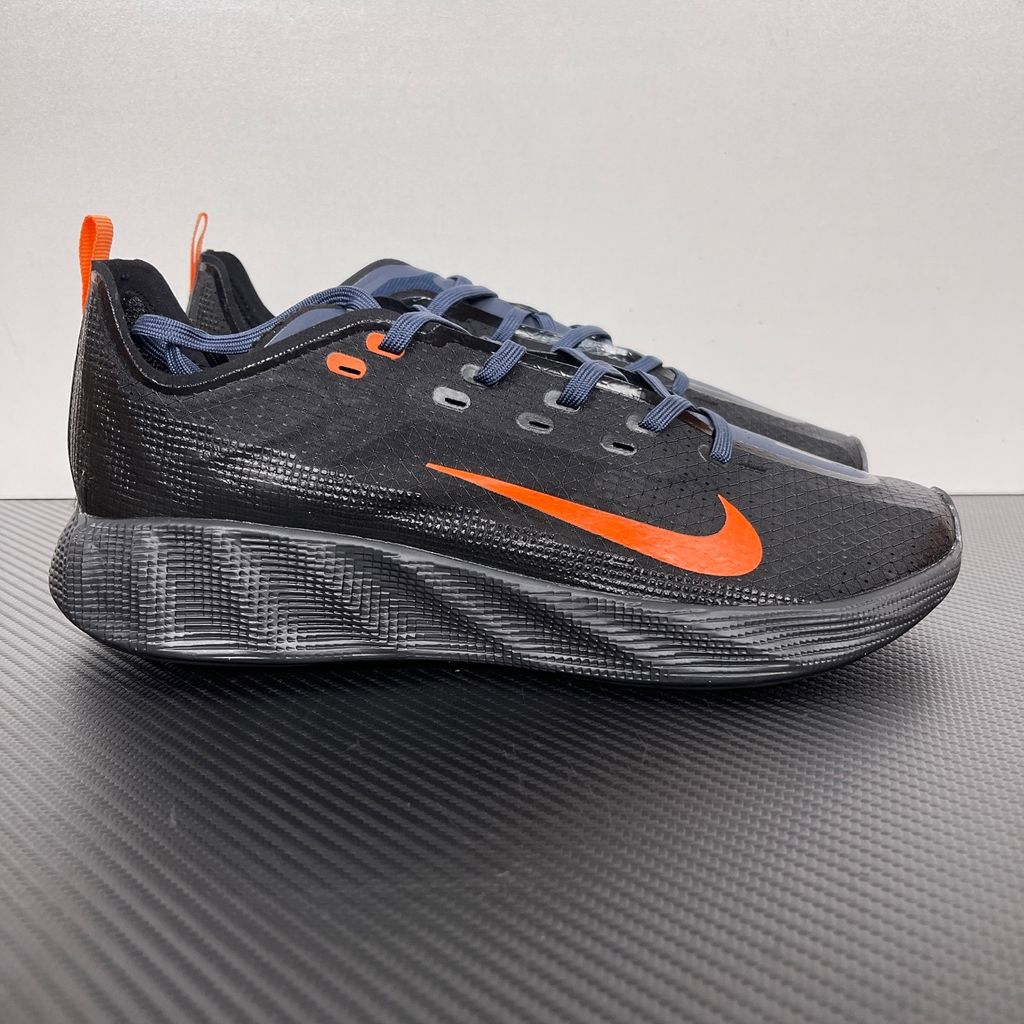 Side profile of the Nike Ava X sneaker in the 'Dark Obsidian Bright Mandarin' colorway, showcasing a deep navy blue breathable mesh upper, vibrant orange contrasting Swoosh and synthetic overlays, and a sculpted, responsive foam midsole.