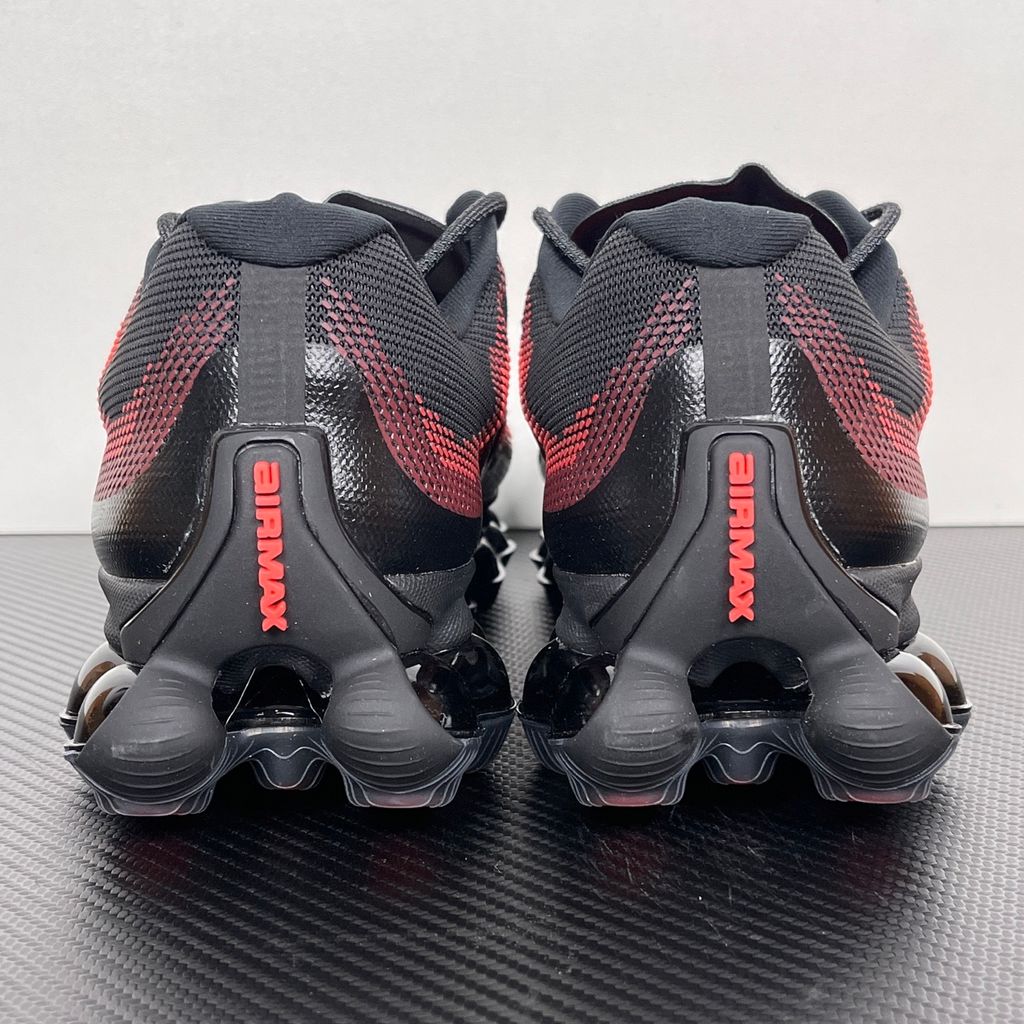 Side profile of the Nike Air Liquid Max sneaker in the 'Bright Crimson Fire Red' colorway, showcasing a fluid, aerodynamic mesh upper with vibrant red and crimson synthetic overlays, and a prominent visible Max Air cushioning unit in the heel and midfoot.