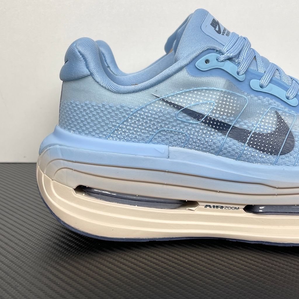 Side profile of the Nike Vomero Premium sneaker in the 'Aluminum' colorway, showcasing the heavily layered breathable mesh upper, cool-toned metallic synthetic overlays, the iconic plastic midfoot cage, and the sculpted Cushlon midsole.