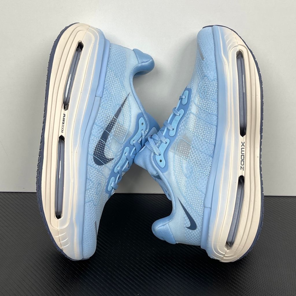 Side profile of the Nike Vomero Premium sneaker in the 'Aluminum' colorway, showcasing the heavily layered breathable mesh upper, cool-toned metallic synthetic overlays, the iconic plastic midfoot cage, and the sculpted Cushlon midsole.
