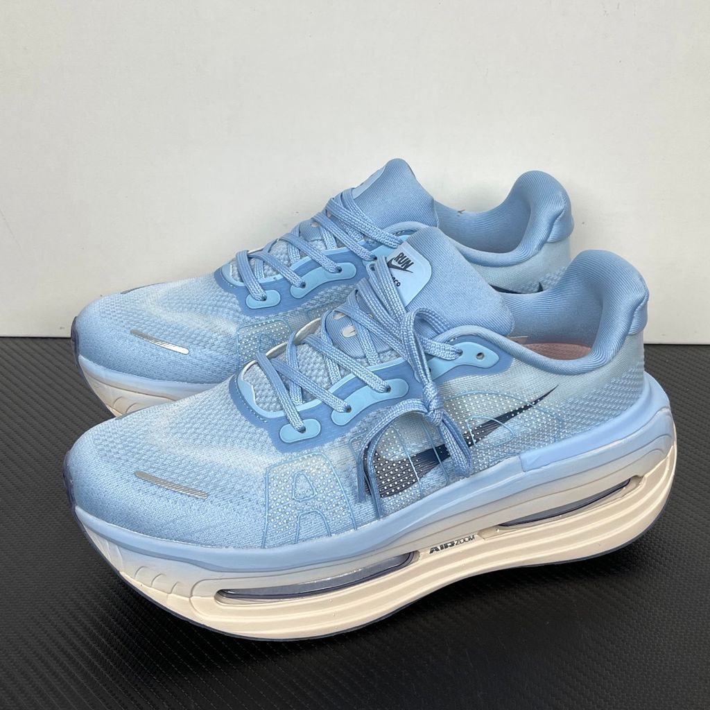 Side profile of the Nike Vomero Premium sneaker in the 'Aluminum' colorway, showcasing the heavily layered breathable mesh upper, cool-toned metallic synthetic overlays, the iconic plastic midfoot cage, and the sculpted Cushlon midsole.