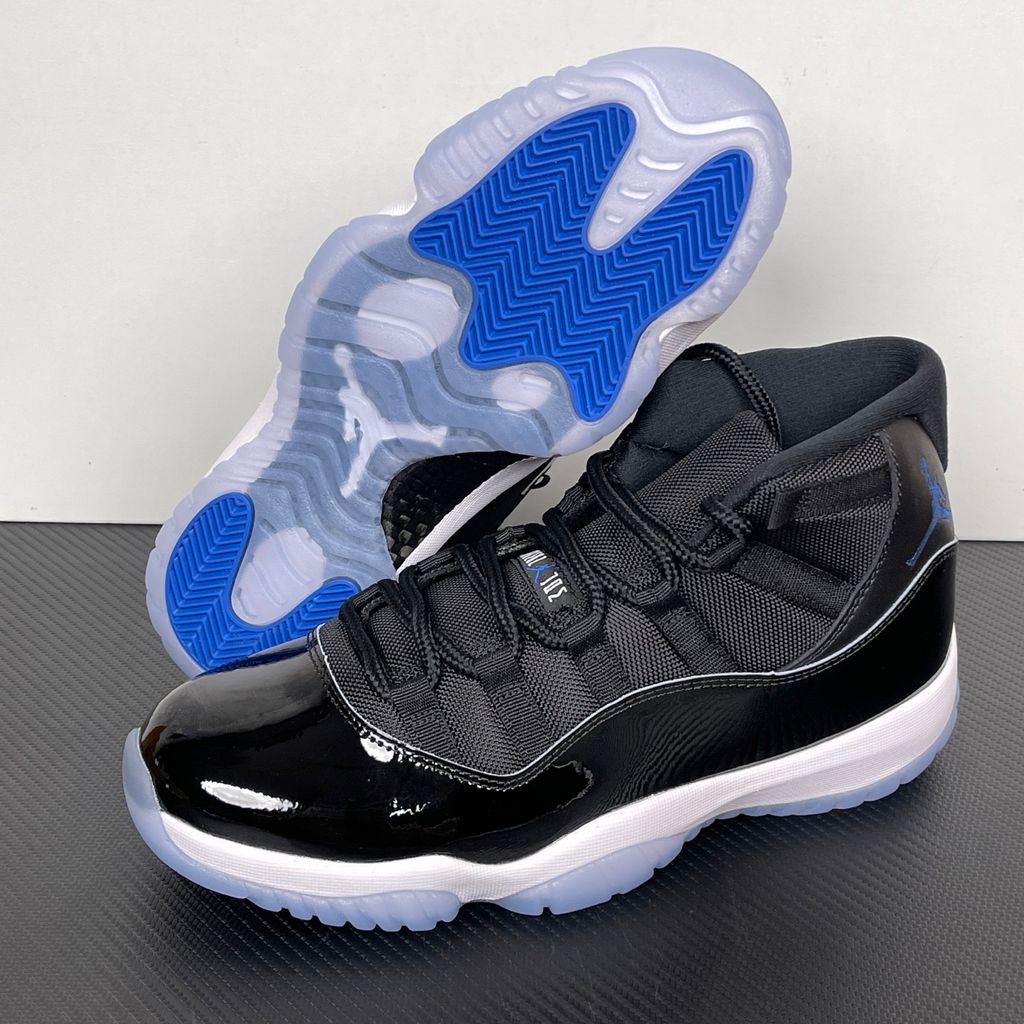 Side profile of the Air Jordan 11 Retro 'Space Jam' (2026), showcasing the high-gloss black patent leather mudguard, premium black mesh upper, white midsole, and the signature icy blue translucent outsole.