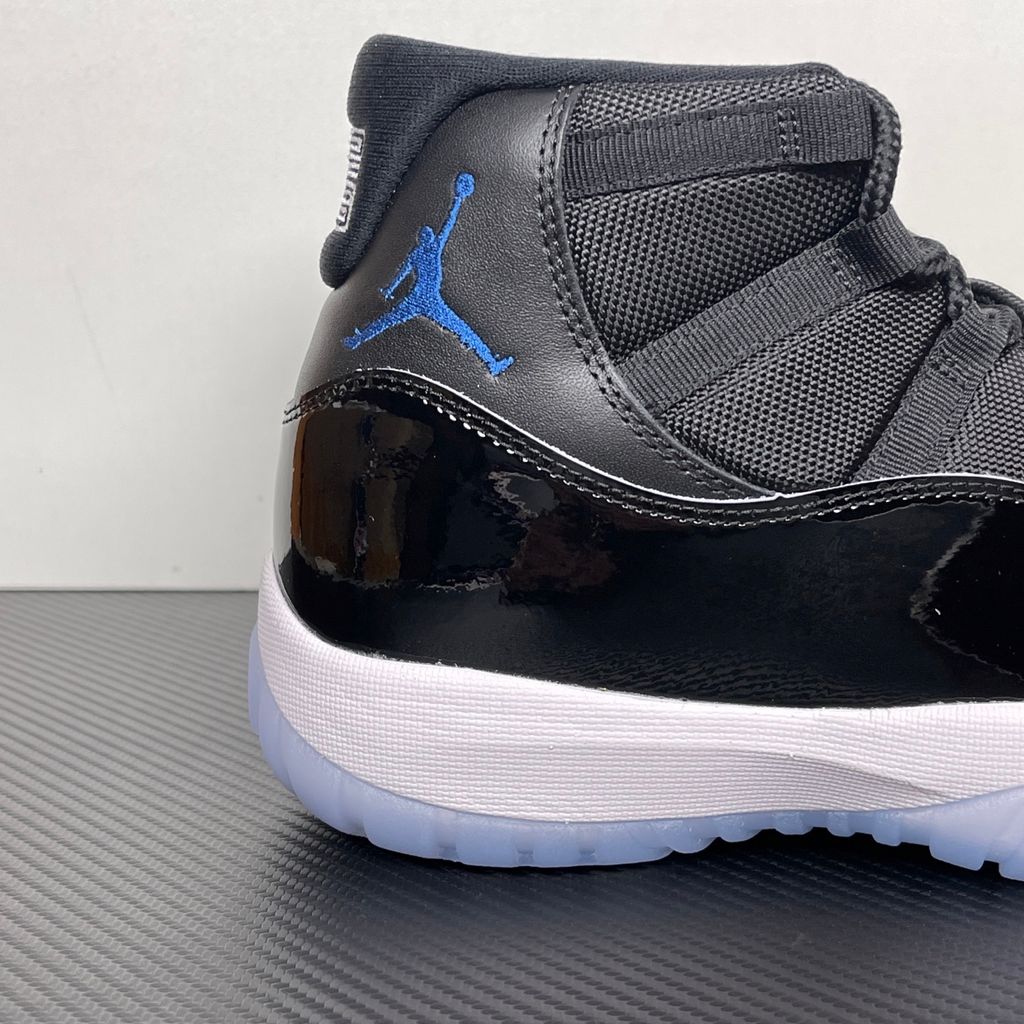 Side profile of the Air Jordan 11 Retro 'Space Jam' (2026), showcasing the high-gloss black patent leather mudguard, premium black mesh upper, white midsole, and the signature icy blue translucent outsole.