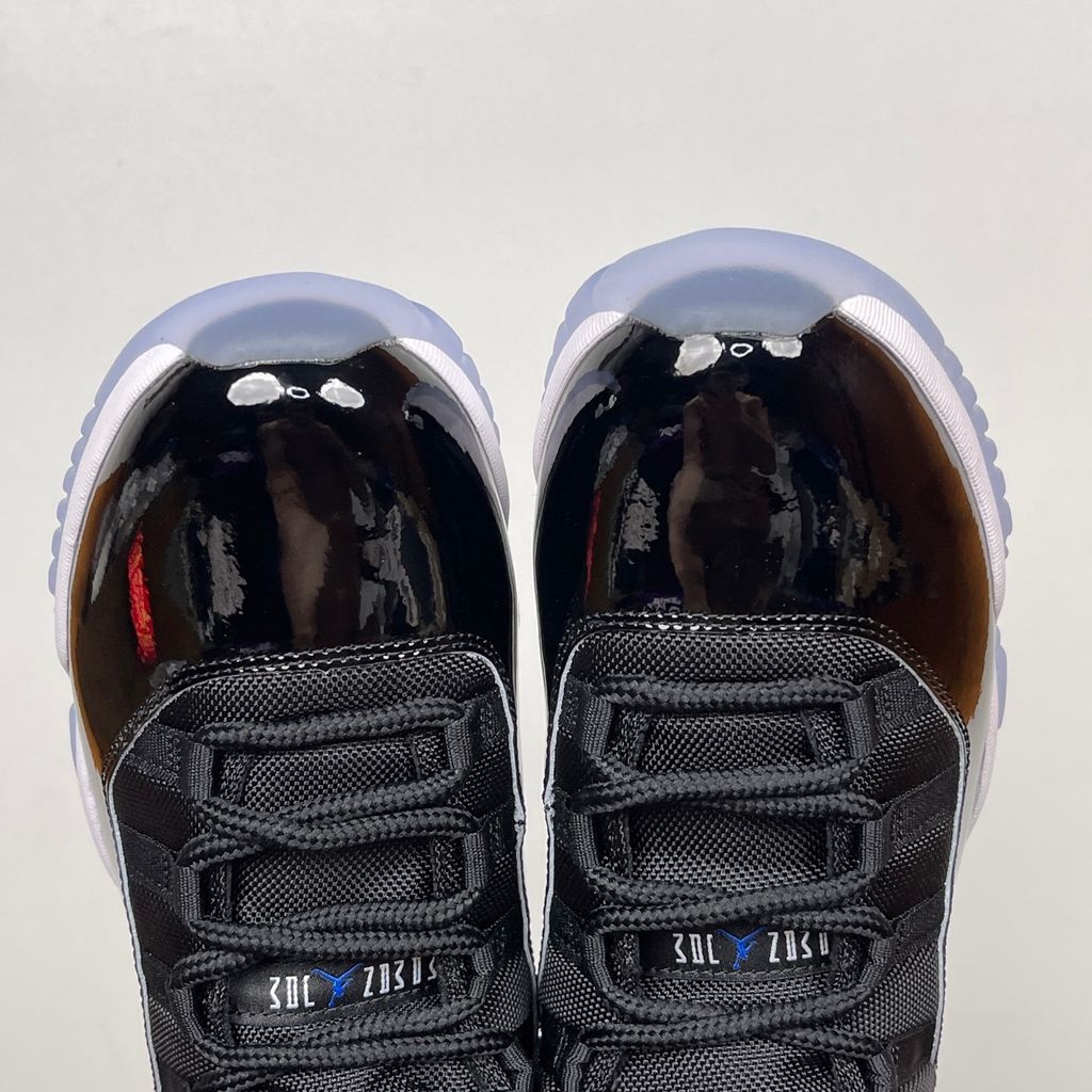 Side profile of the Air Jordan 11 Retro 'Space Jam' (2026), showcasing the high-gloss black patent leather mudguard, premium black mesh upper, white midsole, and the signature icy blue translucent outsole.