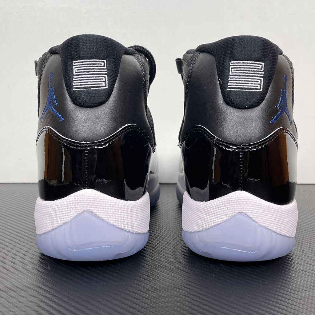 Side profile of the Air Jordan 11 Retro 'Space Jam' (2026), showcasing the high-gloss black patent leather mudguard, premium black mesh upper, white midsole, and the signature icy blue translucent outsole.
