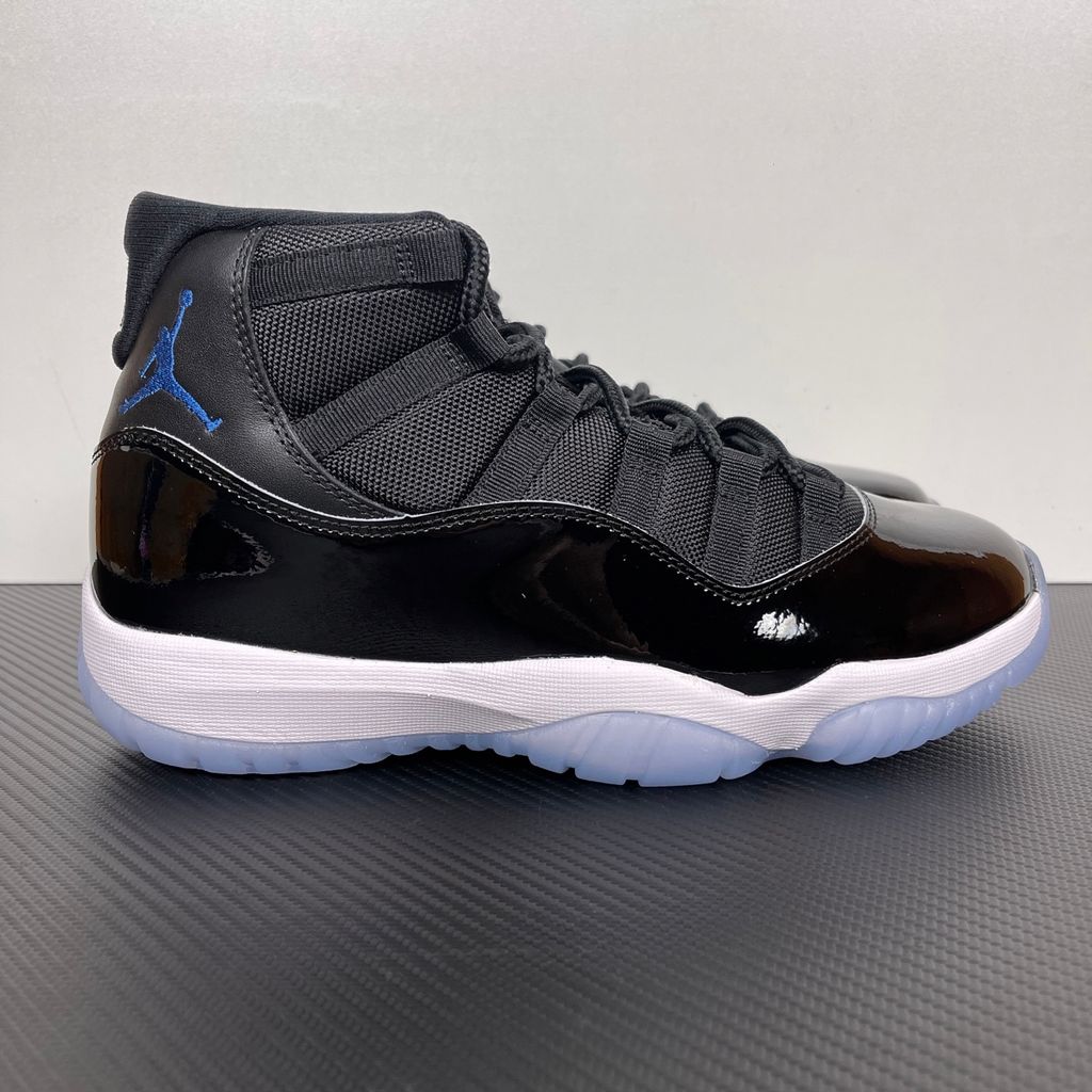 Side profile of the Air Jordan 11 Retro 'Space Jam' (2026), showcasing the high-gloss black patent leather mudguard, premium black mesh upper, white midsole, and the signature icy blue translucent outsole.