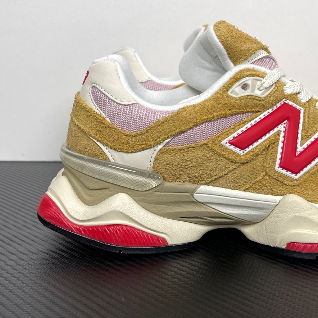 Side profile of the New Balance 9060 sneaker in the striking 'Great Plains True Red' colorway, showcasing the retro-futuristic chunky midsole, highly textured breathable mesh upper with vibrant red suede overlays, and the signature metallic 'N' logo.
