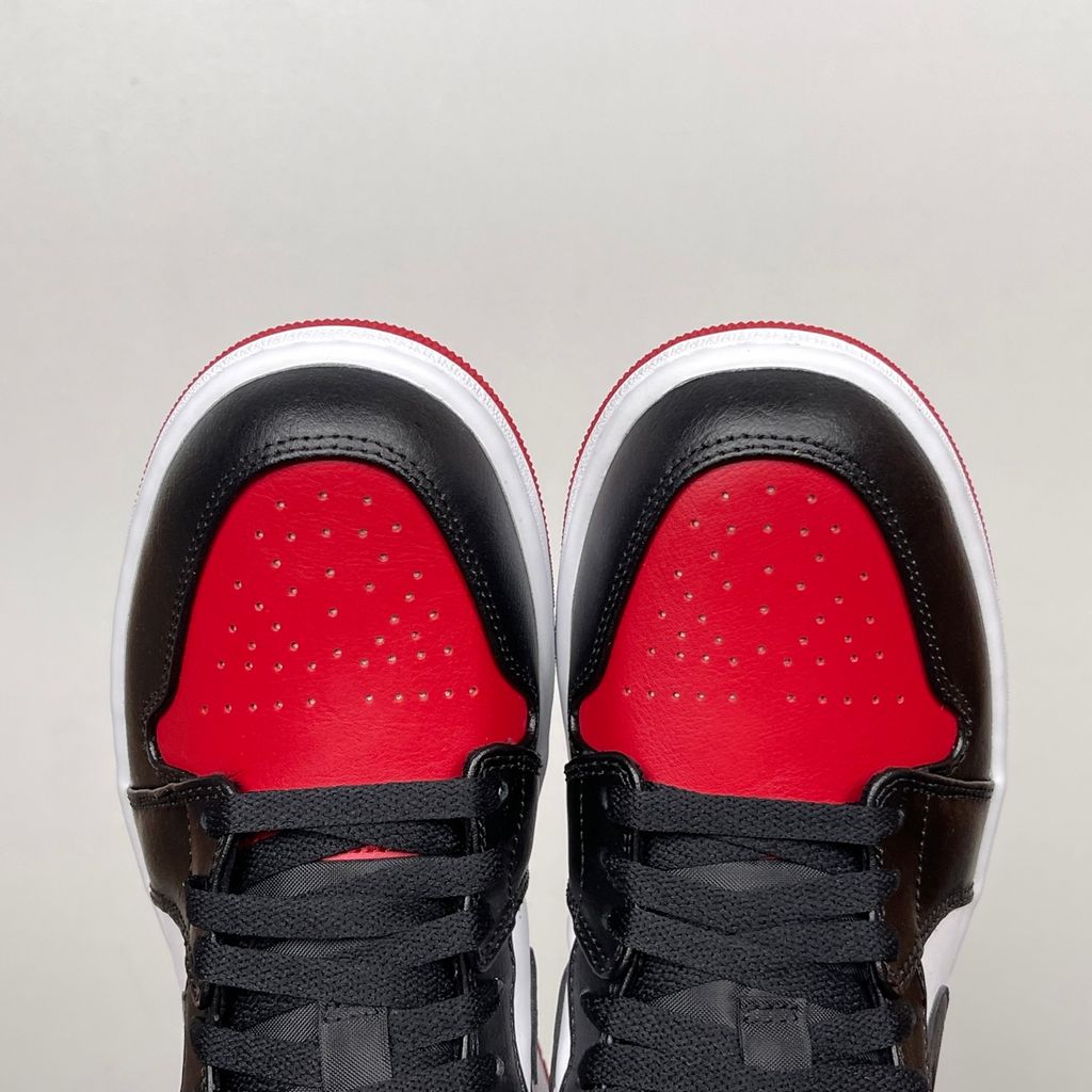 Side profile of the Air Jordan 1 Low 'Bred Toe 2.0' sneaker, showcasing the sharp white, black, and red color blocking, signature Swoosh branding, and the classic low-top profile.