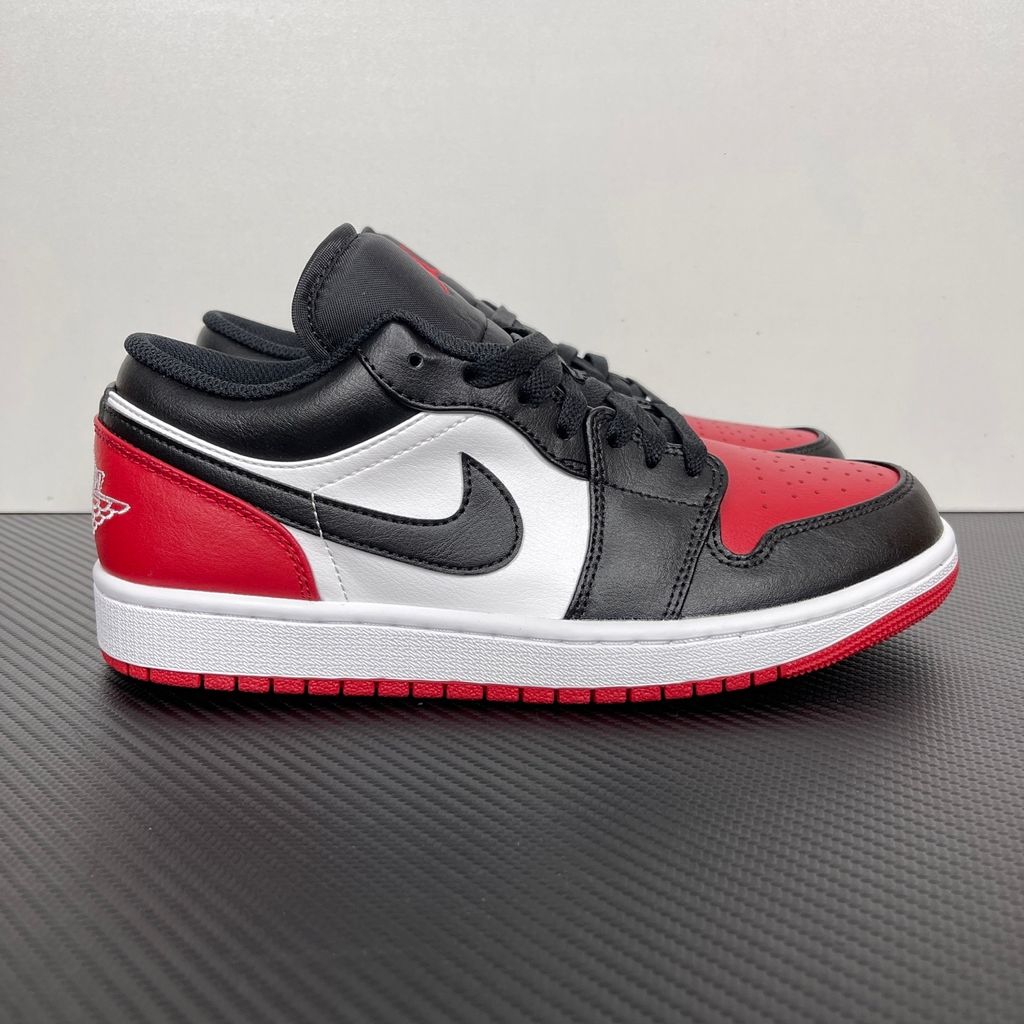 Side profile of the Air Jordan 1 Low 'Bred Toe 2.0' sneaker, showcasing the sharp white, black, and red color blocking, signature Swoosh branding, and the classic low-top profile.