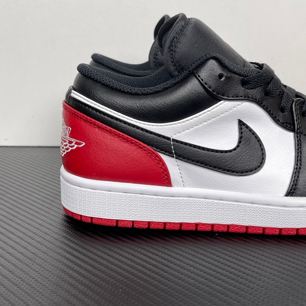 Side profile of the Air Jordan 1 Low 'Bred Toe 2.0' sneaker, showcasing the sharp white, black, and red color blocking, signature Swoosh branding, and the classic low-top profile.