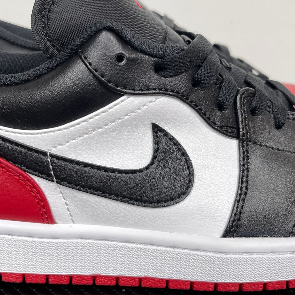 Side profile of the Air Jordan 1 Low 'Bred Toe 2.0' sneaker, showcasing the sharp white, black, and red color blocking, signature Swoosh branding, and the classic low-top profile.