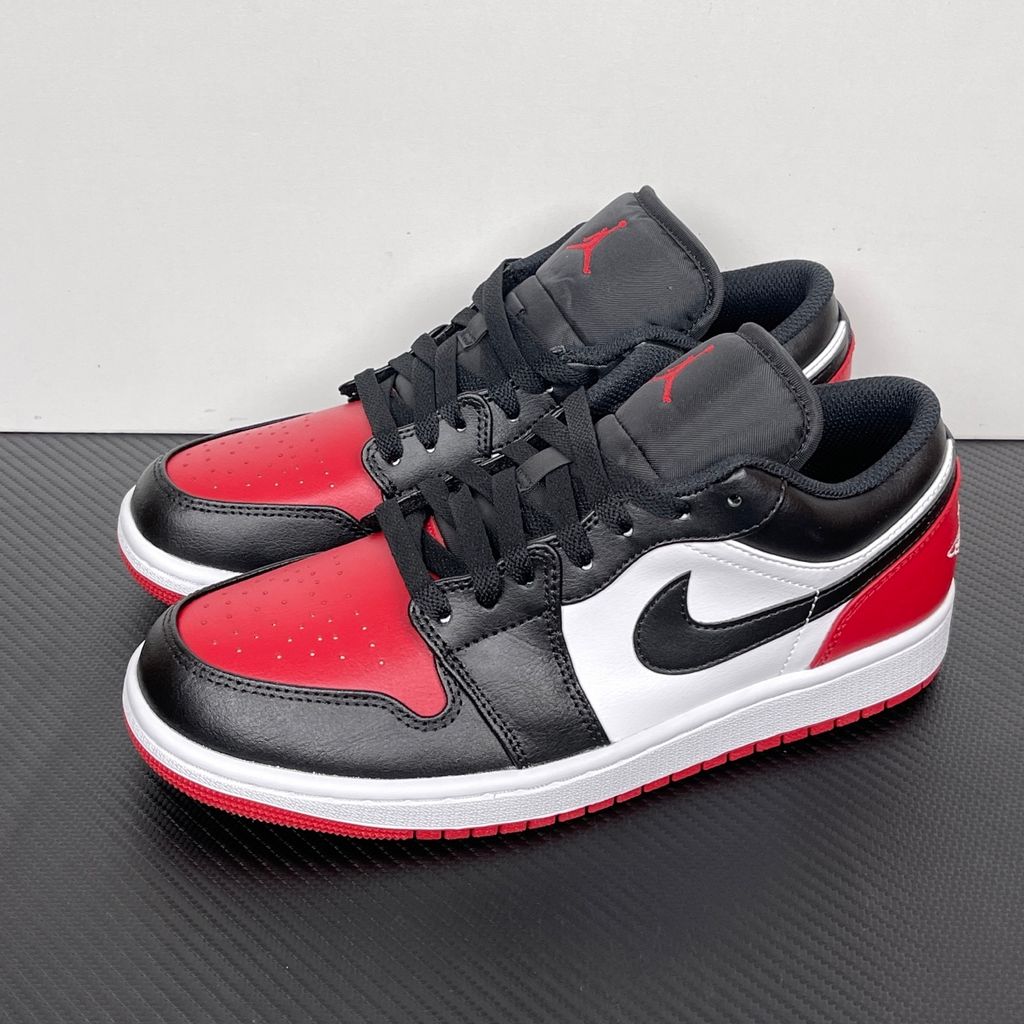 Side profile of the Air Jordan 1 Low 'Bred Toe 2.0' sneaker, showcasing the sharp white, black, and red color blocking, signature Swoosh branding, and the classic low-top profile.