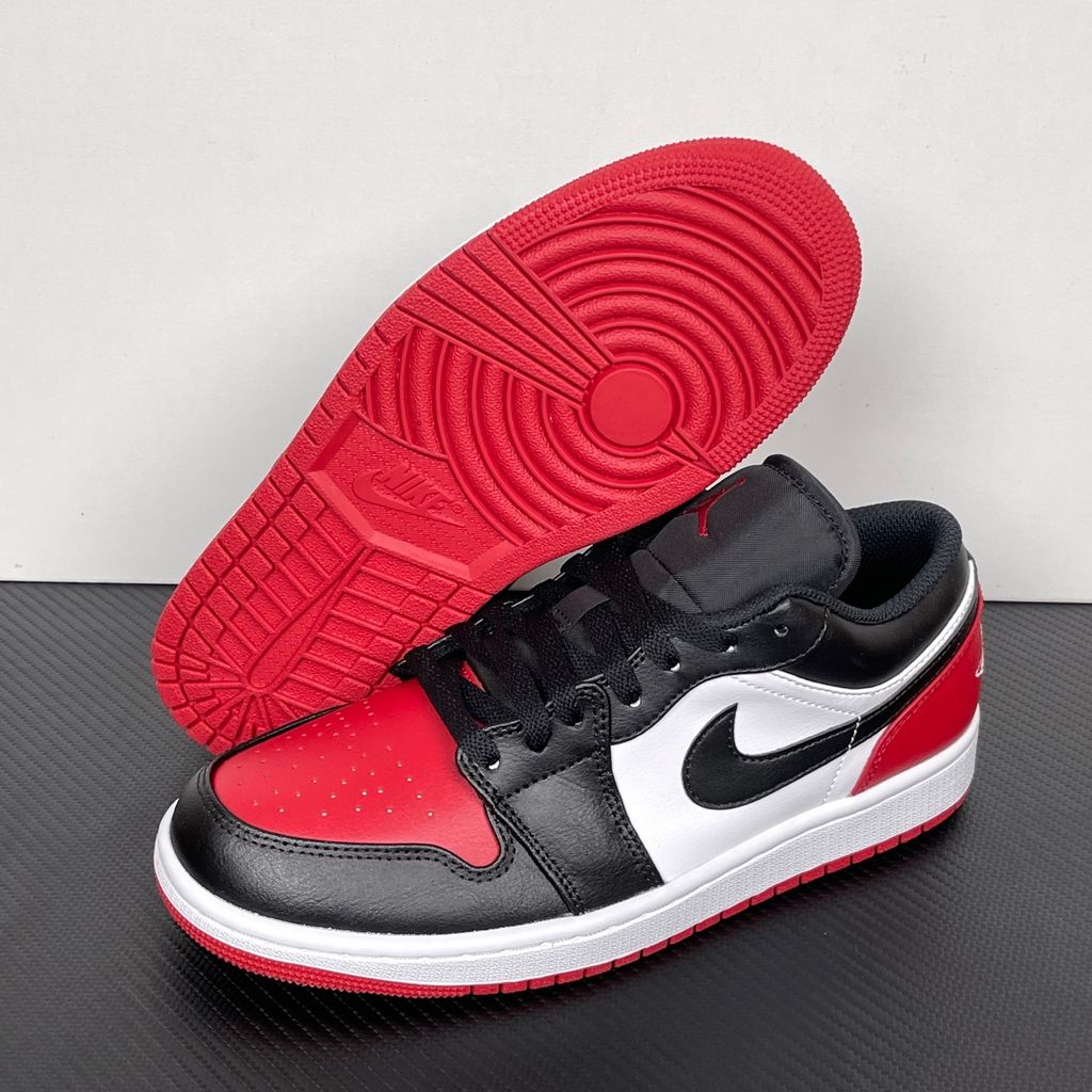 Side profile of the Air Jordan 1 Low 'Bred Toe 2.0' sneaker, showcasing the sharp white, black, and red color blocking, signature Swoosh branding, and the classic low-top profile.