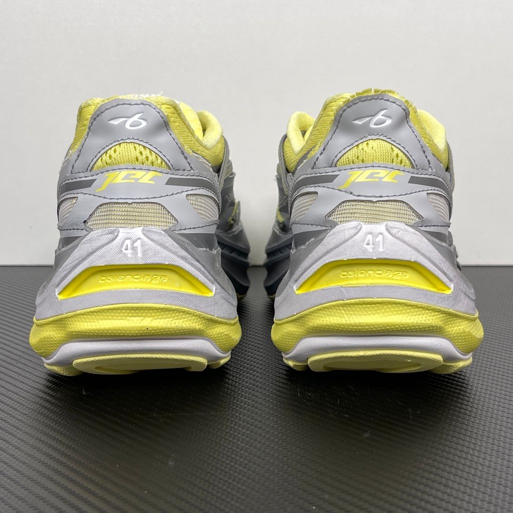 Side profile of the Balenciaga Jet sneaker, highlighting the dynamic grey and light yellow colorway, intricate embossed and printed detailing, and the dramatic 4.25cm thick sculpted sole unit.
