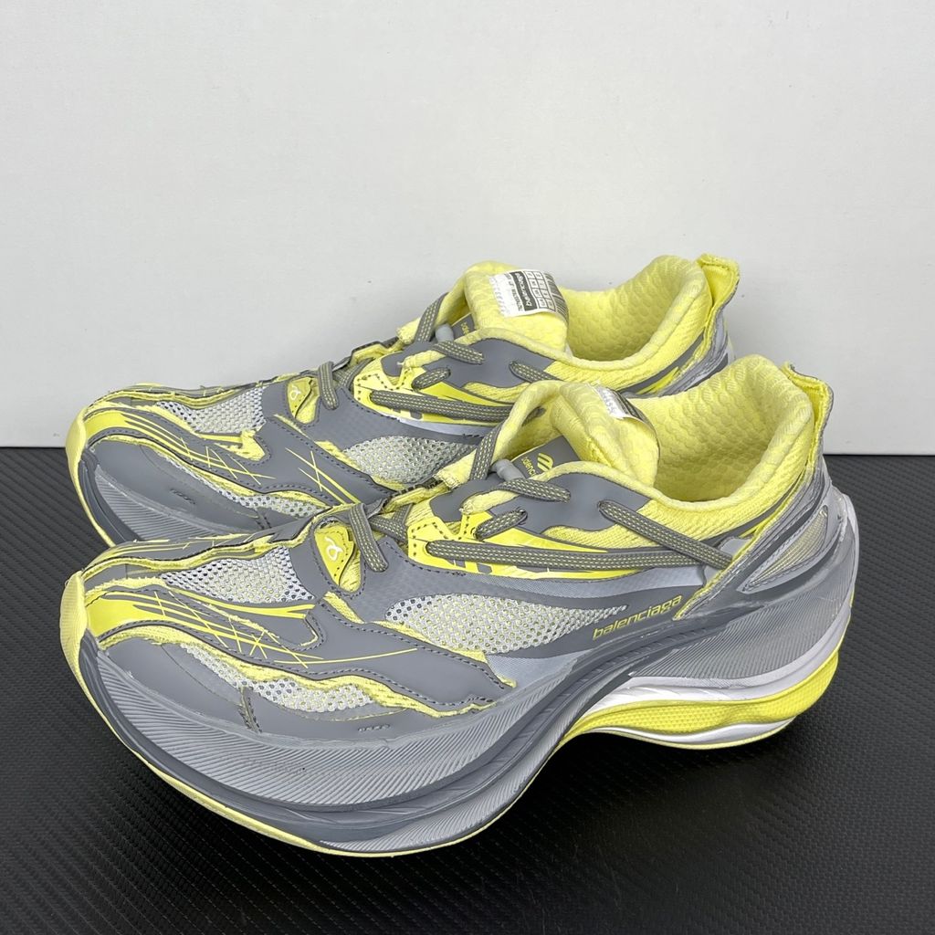 Side profile of the Balenciaga Jet sneaker, highlighting the dynamic grey and light yellow colorway, intricate embossed and printed detailing, and the dramatic 4.25cm thick sculpted sole unit.