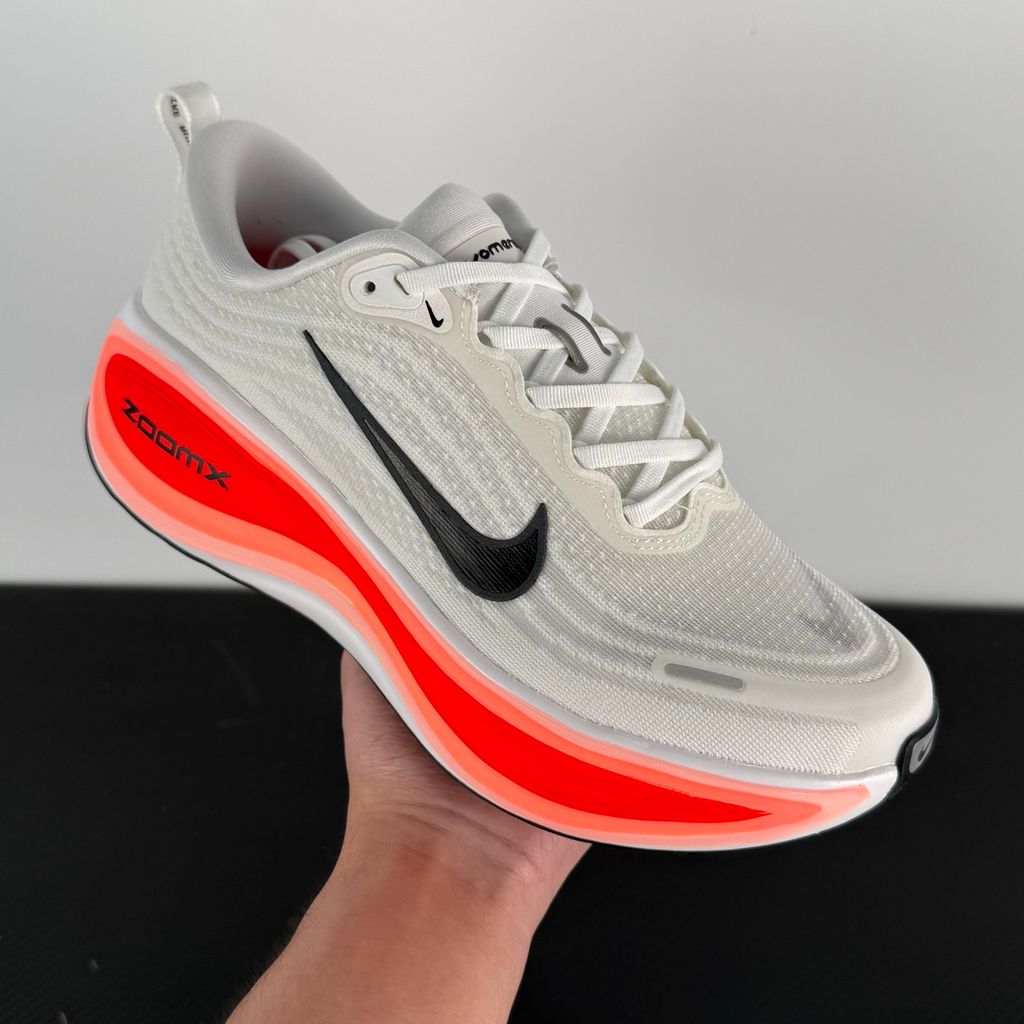 Side profile of the Nike Vomero Plus sneaker in the 'White Black Bright Crimson' colorway, showcasing the clean white mesh base, bold black synthetic overlays, and striking Bright Crimson accents on the midsole and branding.