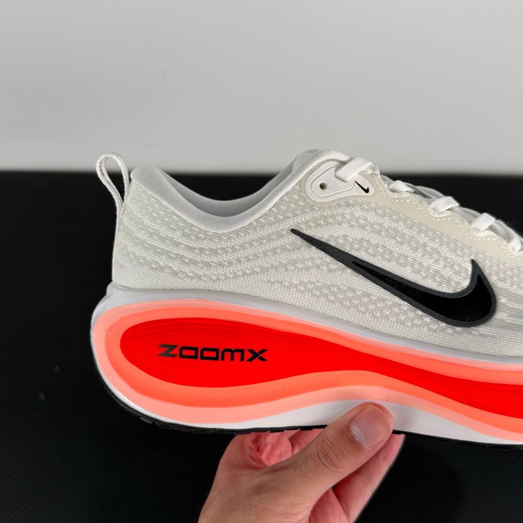 Side profile of the Nike Vomero Plus sneaker in the 'White Black Bright Crimson' colorway, showcasing the clean white mesh base, bold black synthetic overlays, and striking Bright Crimson accents on the midsole and branding.