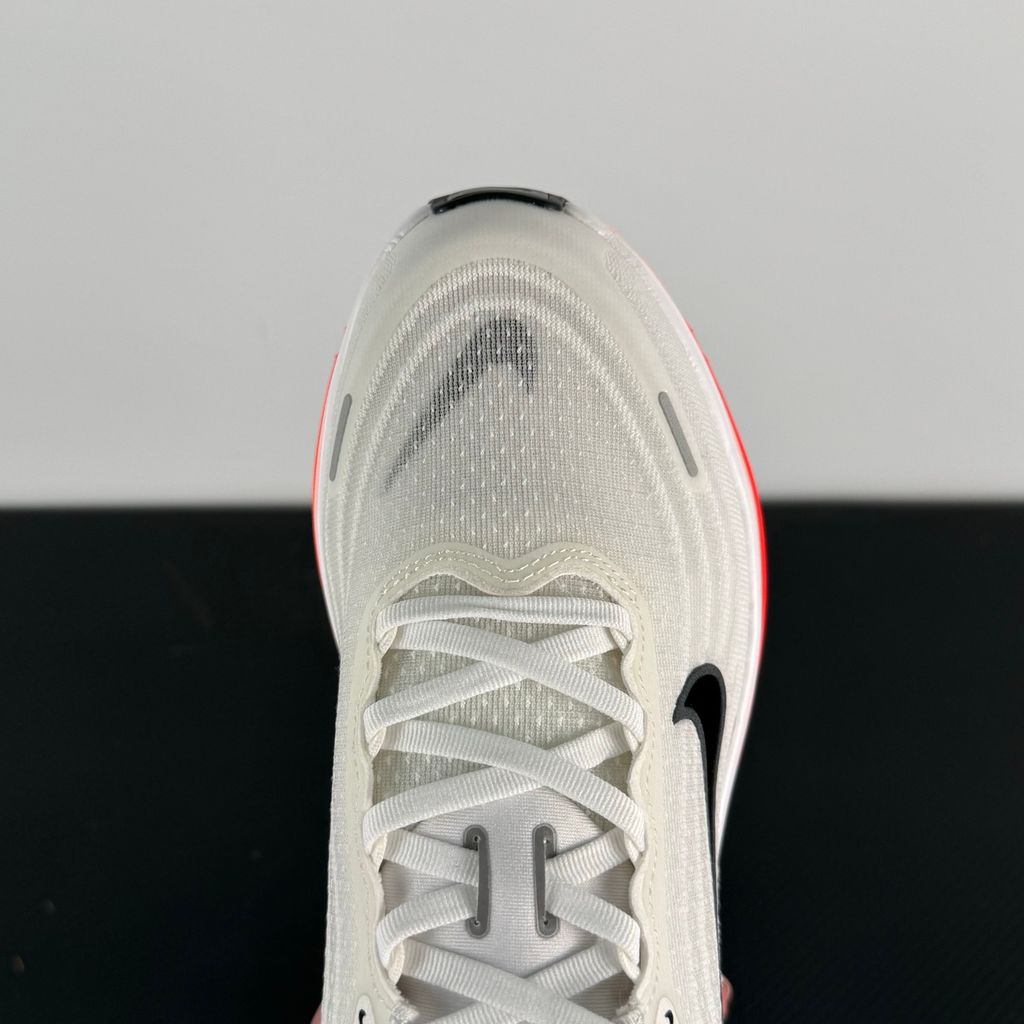 Side profile of the Nike Vomero Plus sneaker in the 'White Black Bright Crimson' colorway, showcasing the clean white mesh base, bold black synthetic overlays, and striking Bright Crimson accents on the midsole and branding.
