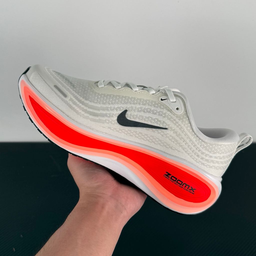 Side profile of the Nike Vomero Plus sneaker in the 'White Black Bright Crimson' colorway, showcasing the clean white mesh base, bold black synthetic overlays, and striking Bright Crimson accents on the midsole and branding.