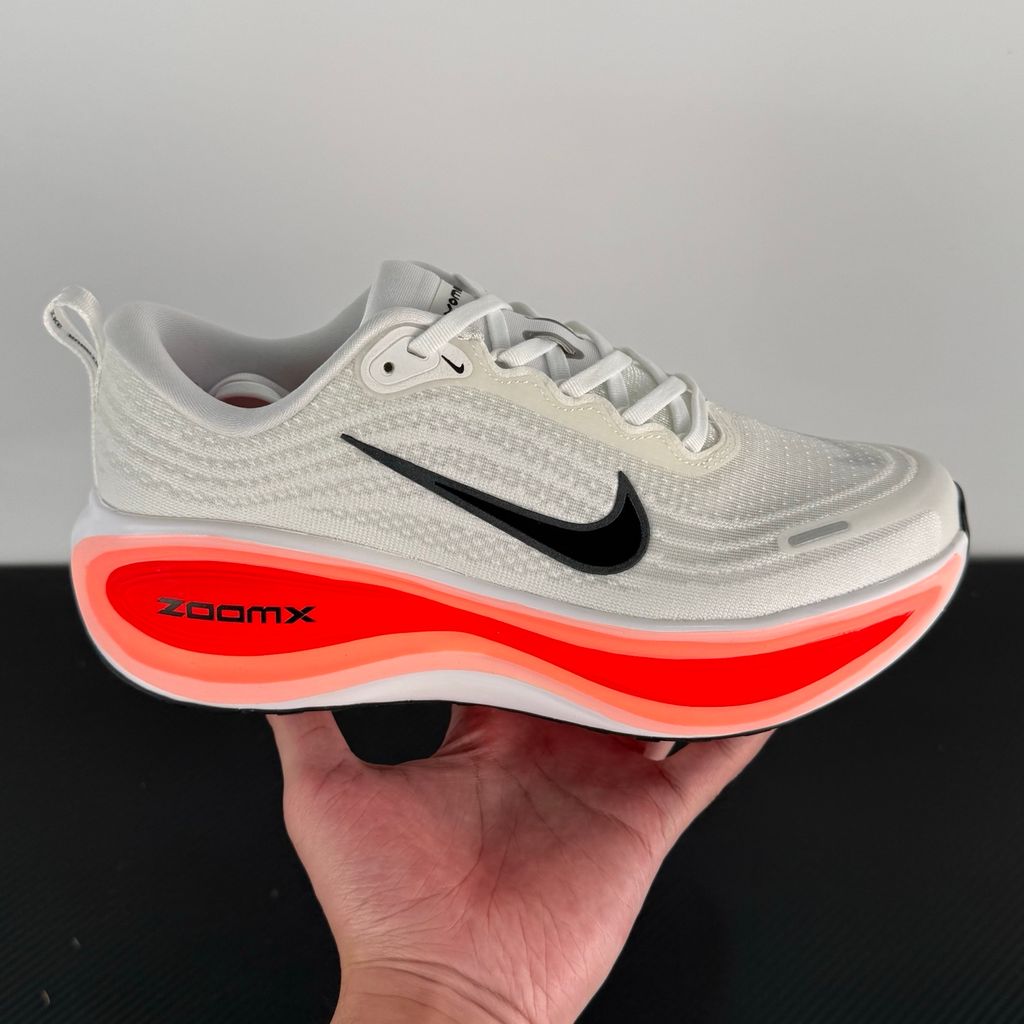 Side profile of the Nike Vomero Plus sneaker in the 'White Black Bright Crimson' colorway, showcasing the clean white mesh base, bold black synthetic overlays, and striking Bright Crimson accents on the midsole and branding.