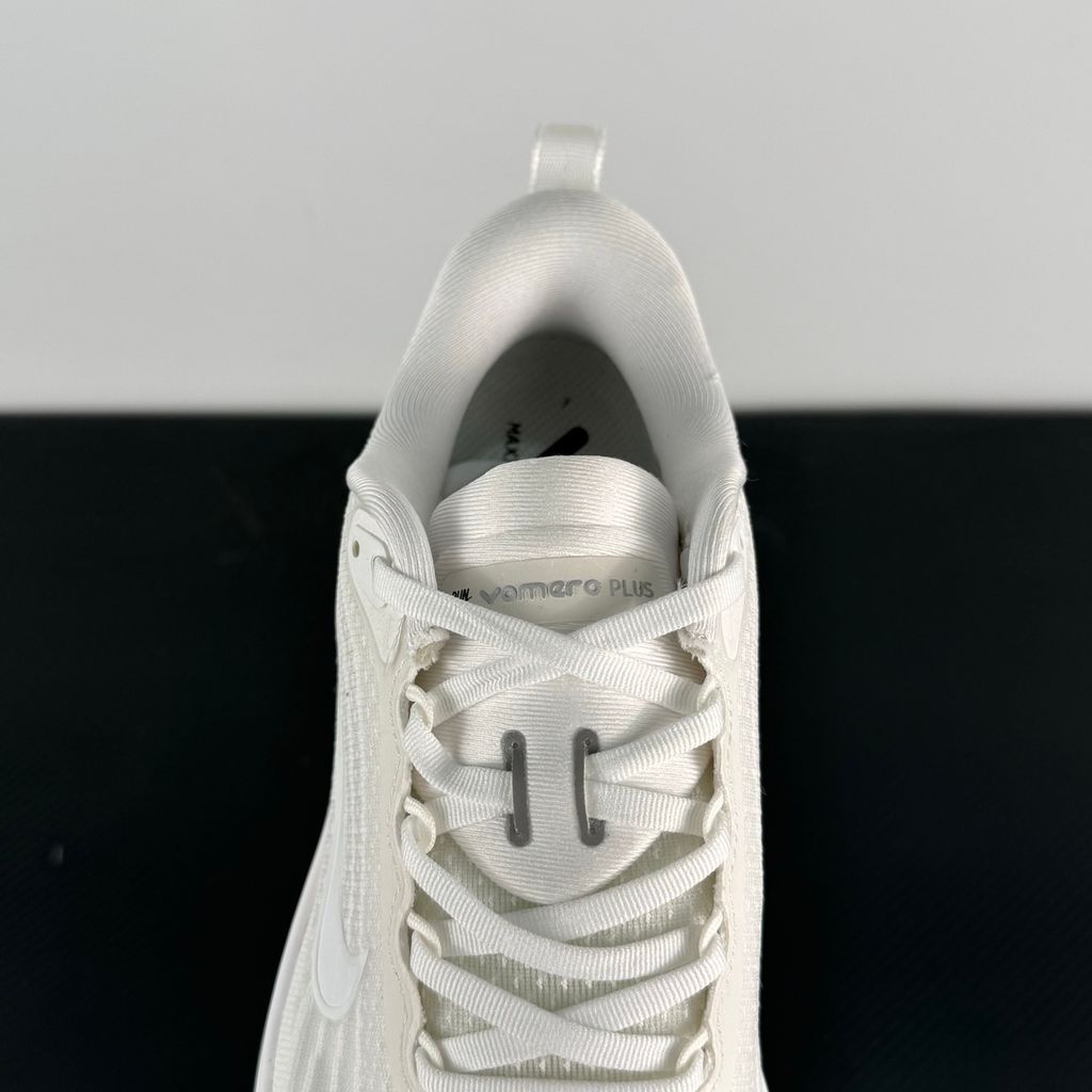 Side profile of the Nike Vomero Plus sneaker in the 'White' colorway, showcasing the clean, monochromatic mesh upper, tonal synthetic overlays, and the sculpted, high-performance foam midsole.