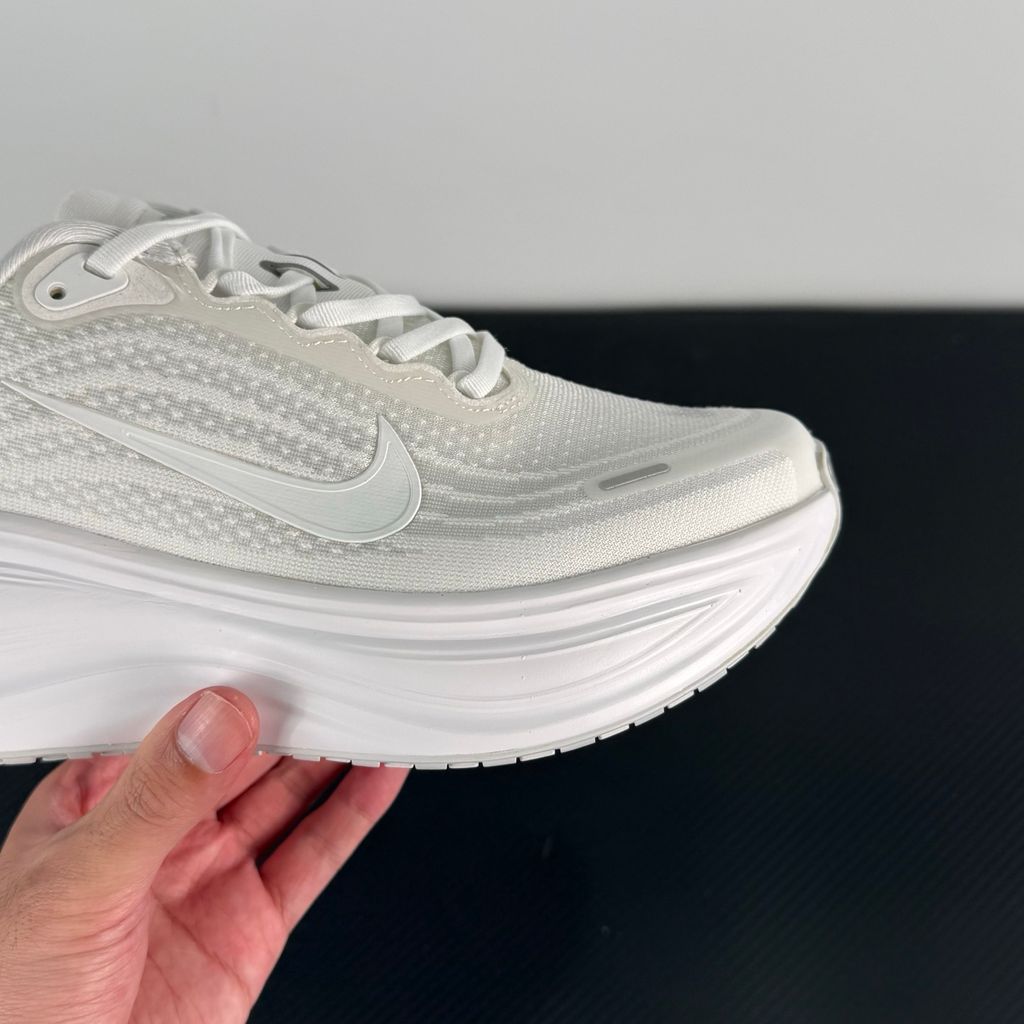 Side profile of the Nike Vomero Plus sneaker in the 'White' colorway, showcasing the clean, monochromatic mesh upper, tonal synthetic overlays, and the sculpted, high-performance foam midsole.