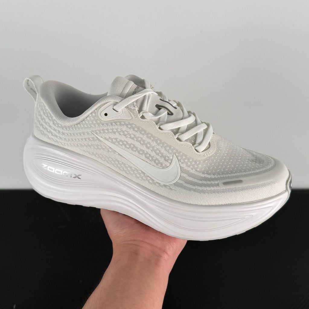Side profile of the Nike Vomero Plus sneaker in the 'White' colorway, showcasing the clean, monochromatic mesh upper, tonal synthetic overlays, and the sculpted, high-performance foam midsole.