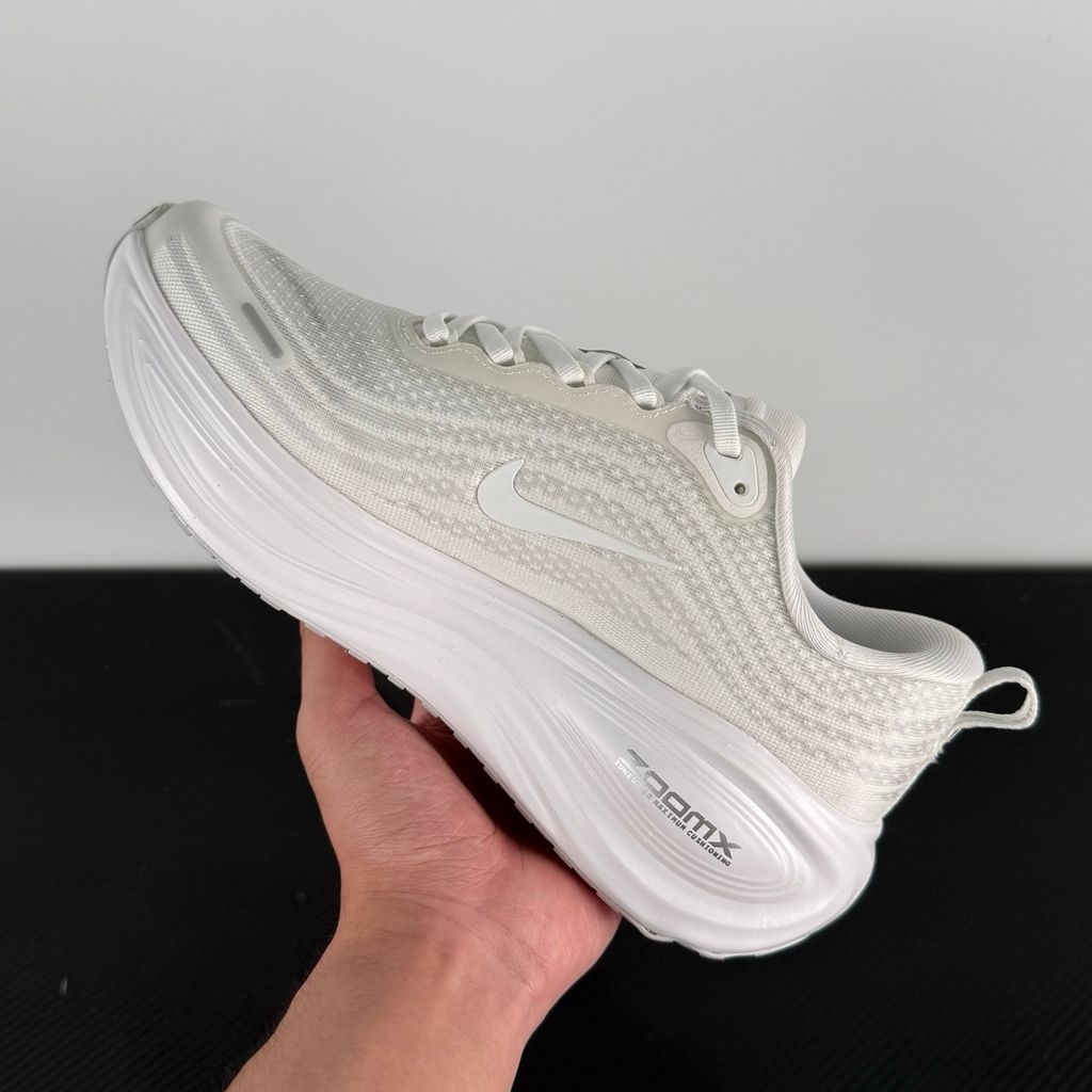 Side profile of the Nike Vomero Plus sneaker in the 'White' colorway, showcasing the clean, monochromatic mesh upper, tonal synthetic overlays, and the sculpted, high-performance foam midsole.