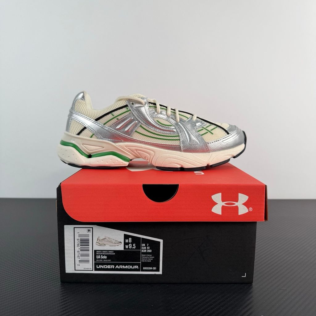 Side profile of the Under Armour SolaStone sneaker, highlighting the shimmering metallic silver upper, bold team kelly green branding and midsole accents, and the streamlined, athletic silhouette.