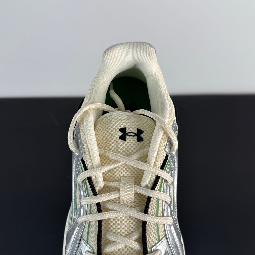 Side profile of the Under Armour SolaStone sneaker, highlighting the shimmering metallic silver upper, bold team kelly green branding and midsole accents, and the streamlined, athletic silhouette.