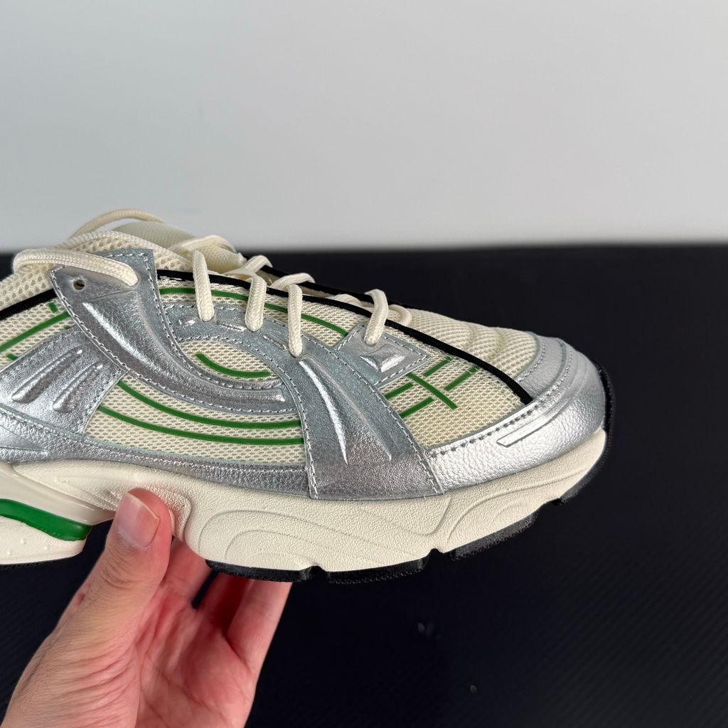 Side profile of the Under Armour SolaStone sneaker, highlighting the shimmering metallic silver upper, bold team kelly green branding and midsole accents, and the streamlined, athletic silhouette.