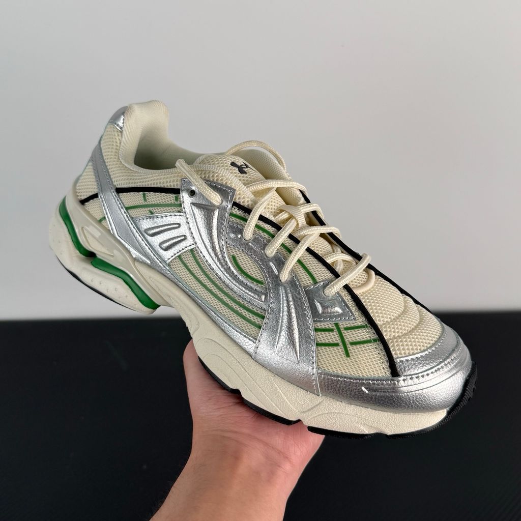 Side profile of the Under Armour SolaStone sneaker, highlighting the shimmering metallic silver upper, bold team kelly green branding and midsole accents, and the streamlined, athletic silhouette.