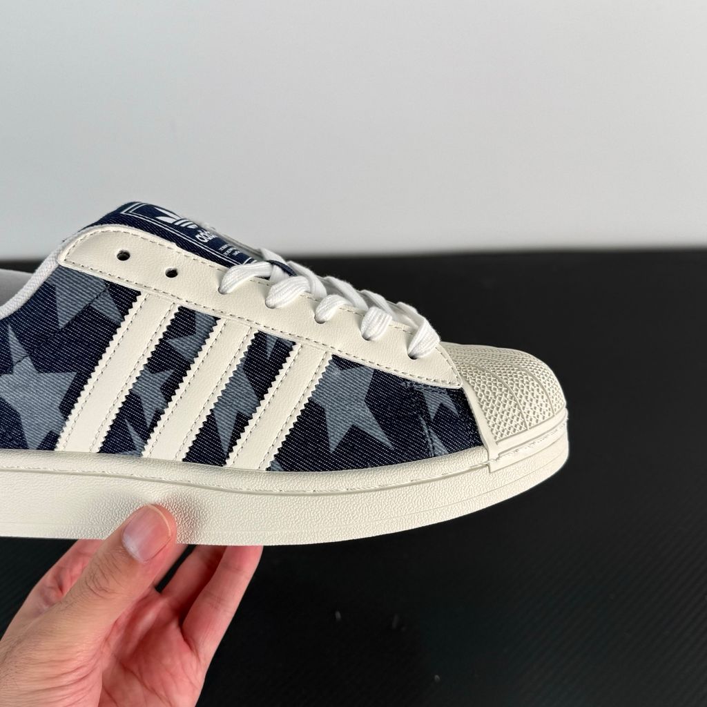 Side profile of the adidas Superstar II 'Denim Star' sneaker, showcasing the textured denim-style upper, classic serrated Three-Stripes branding, and the signature white rubber shell toe.