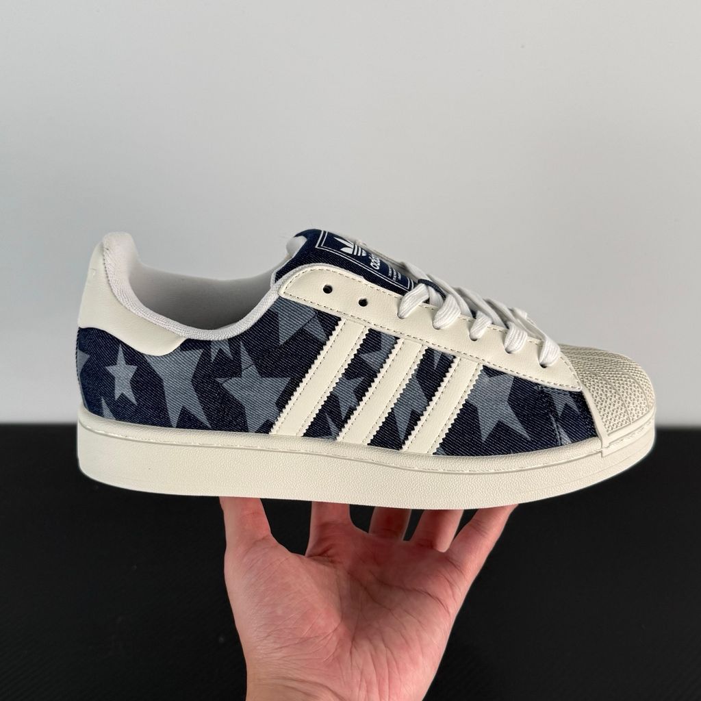 Side profile of the adidas Superstar II 'Denim Star' sneaker, showcasing the textured denim-style upper, classic serrated Three-Stripes branding, and the signature white rubber shell toe.