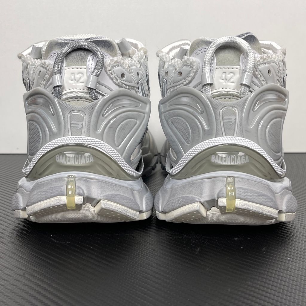 Side profile of the Balenciaga Runner sneaker in the 'White Silver' colorway, highlighting the complex multi-layered construction, distressed technical mesh and synthetic overlays, and the iconic dynamic sole unit.