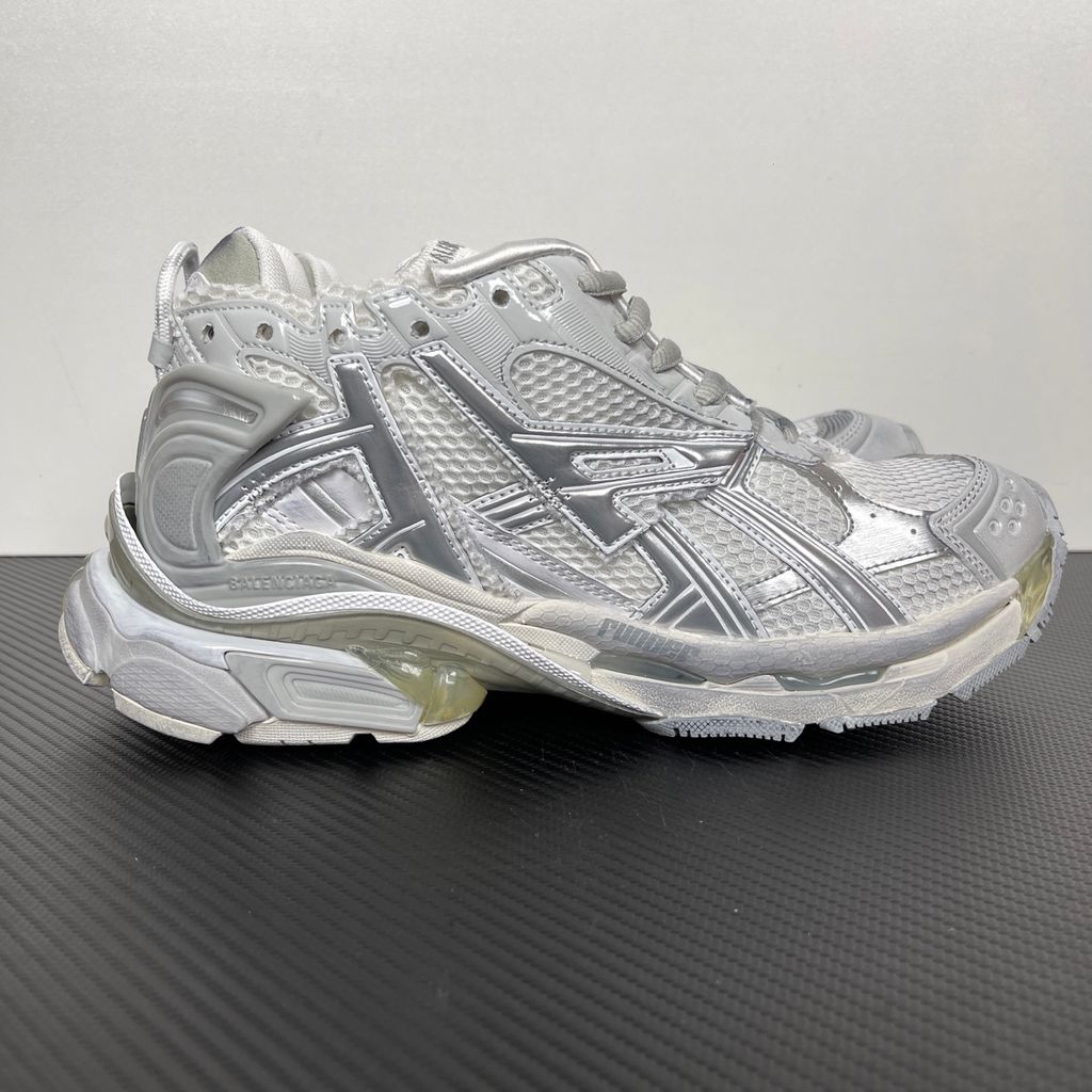 Side profile of the Balenciaga Runner sneaker in the 'White Silver' colorway, highlighting the complex multi-layered construction, distressed technical mesh and synthetic overlays, and the iconic dynamic sole unit.