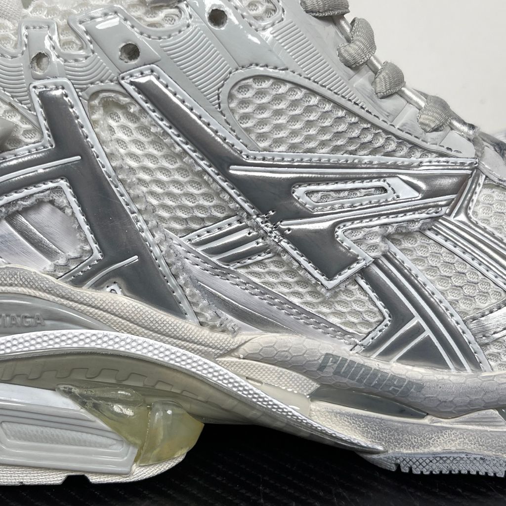 Side profile of the Balenciaga Runner sneaker in the 'White Silver' colorway, highlighting the complex multi-layered construction, distressed technical mesh and synthetic overlays, and the iconic dynamic sole unit.