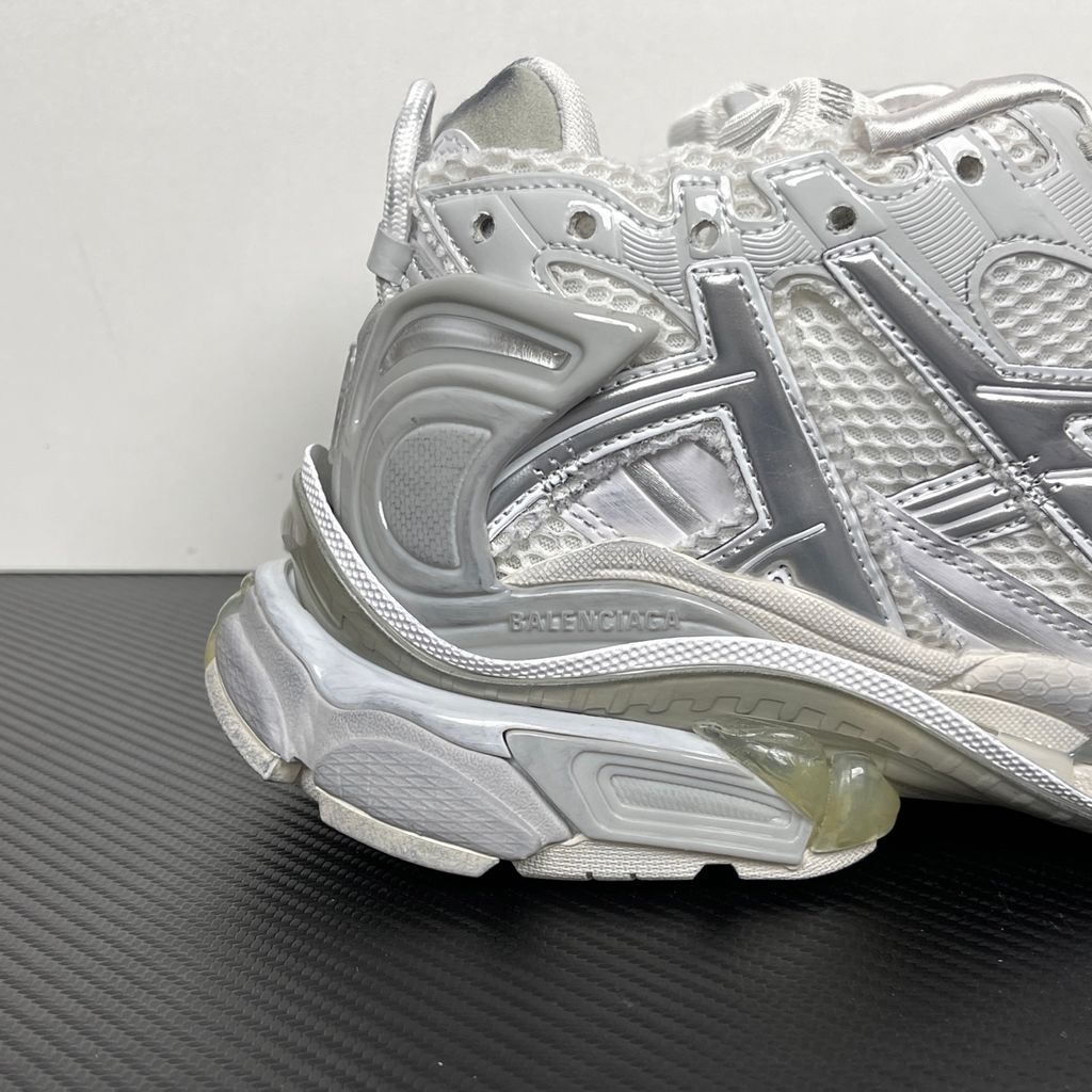 Side profile of the Balenciaga Runner sneaker in the 'White Silver' colorway, highlighting the complex multi-layered construction, distressed technical mesh and synthetic overlays, and the iconic dynamic sole unit.
