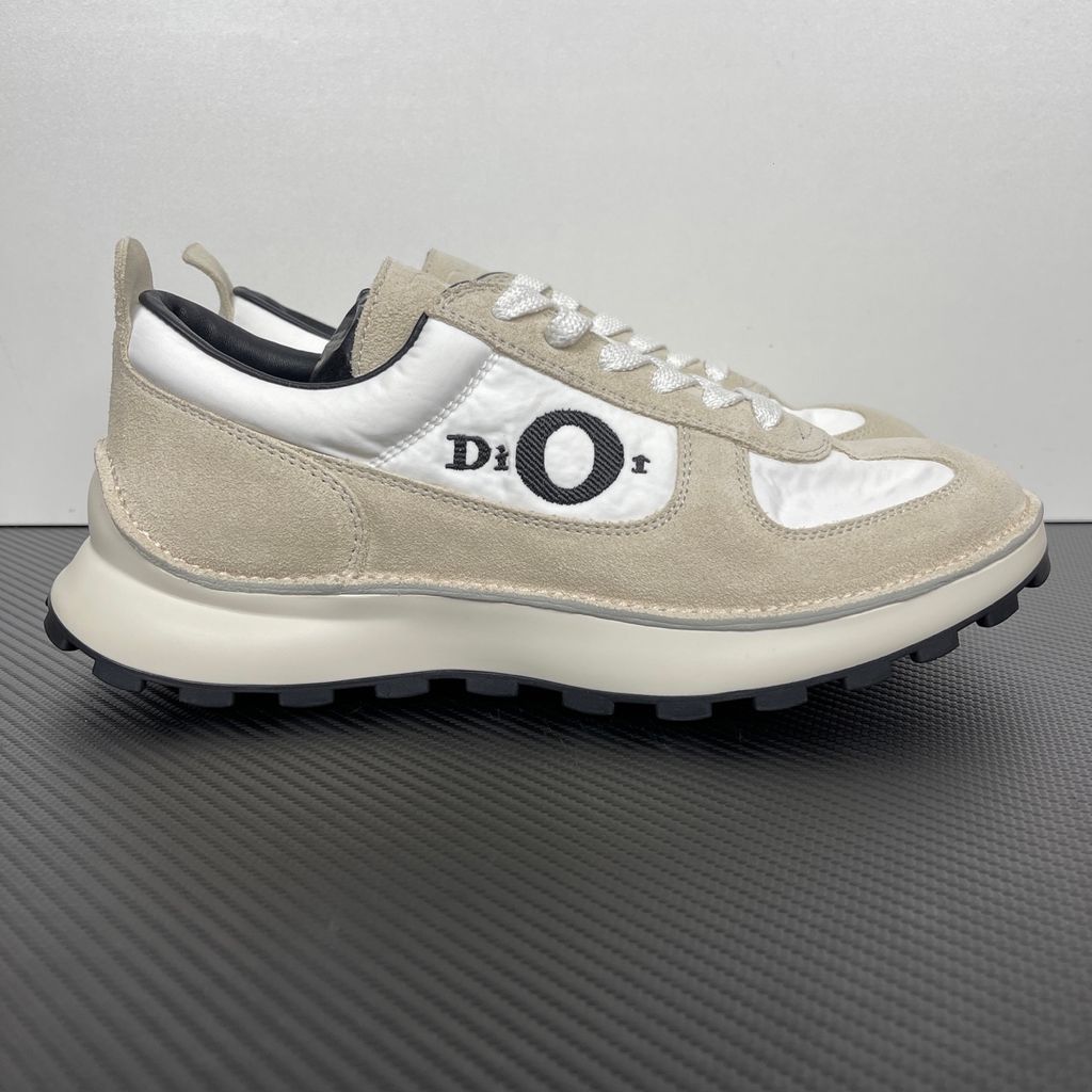 Side profile of the Dior Squash Sneaker, showcasing the white nylon base, beige suede overlays, prominent black "DiOr" side logo, and chunky white midsole with a black lugged outsole.