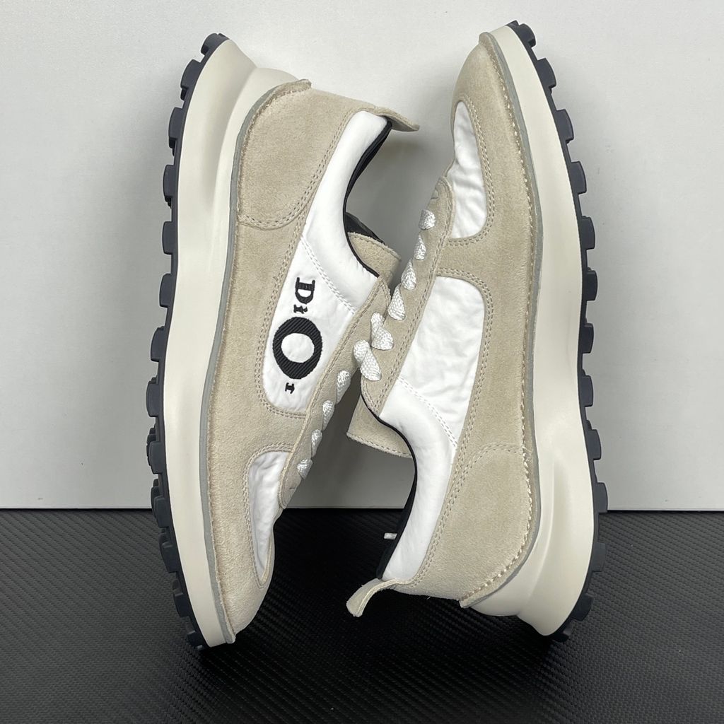 Side profile of the Dior Squash Sneaker, showcasing the white nylon base, beige suede overlays, prominent black "DiOr" side logo, and chunky white midsole with a black lugged outsole.