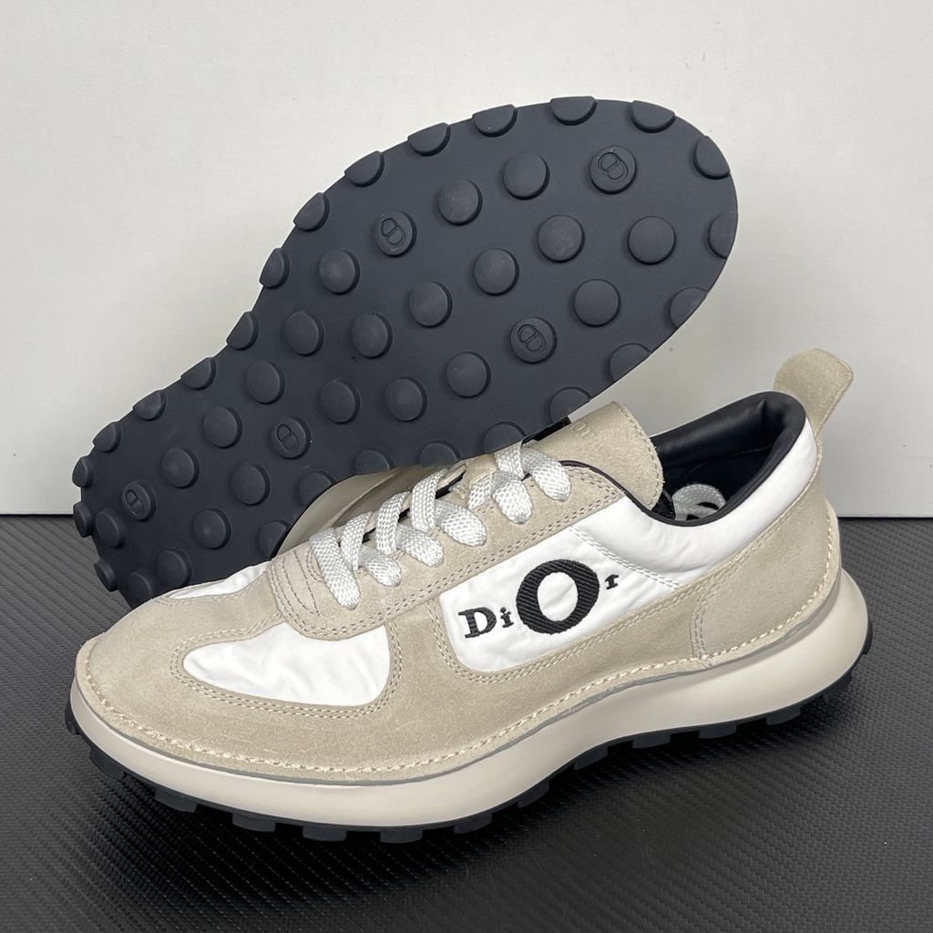 Side profile of the Dior Squash Sneaker, showcasing the white nylon base, beige suede overlays, prominent black "DiOr" side logo, and chunky white midsole with a black lugged outsole.