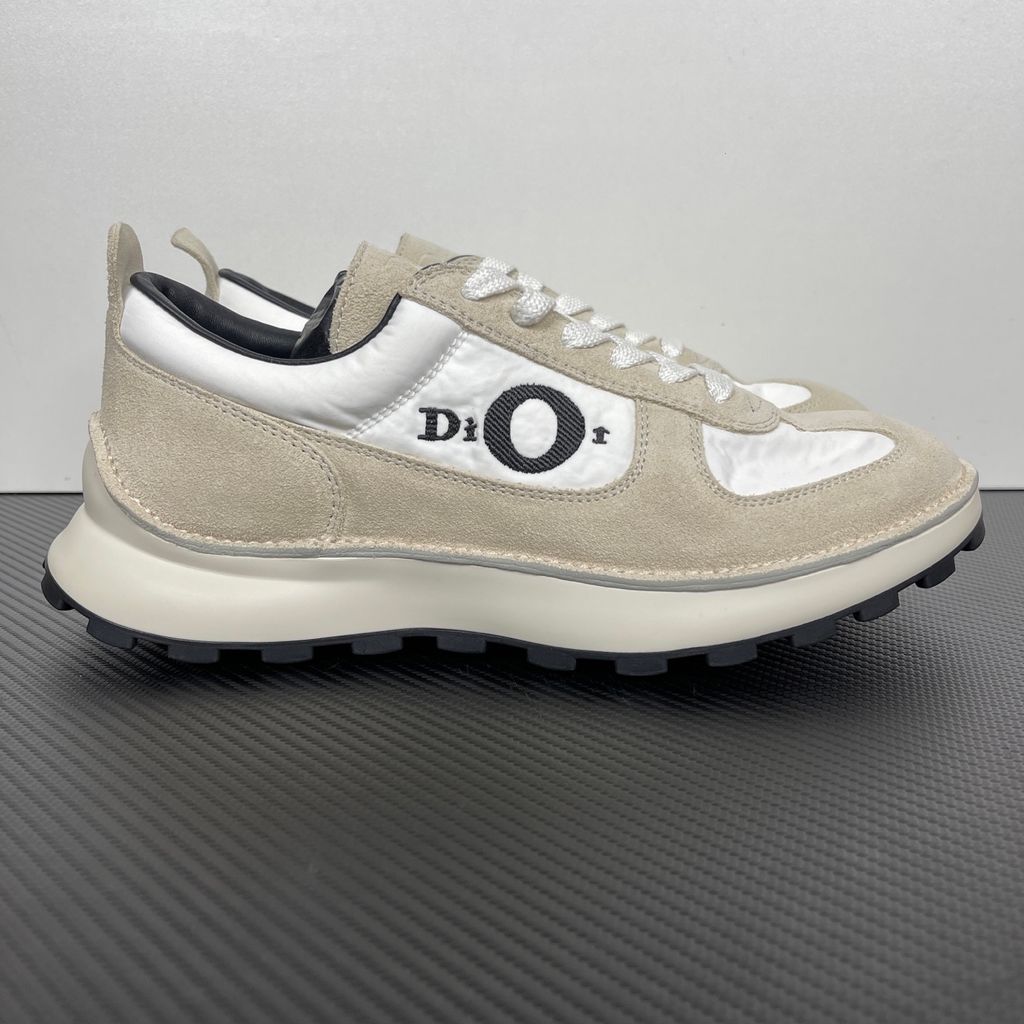 Side profile of the Dior Squash Sneaker, showcasing the white nylon base, beige suede overlays, prominent black "DiOr" side logo, and chunky white midsole with a black lugged outsole.