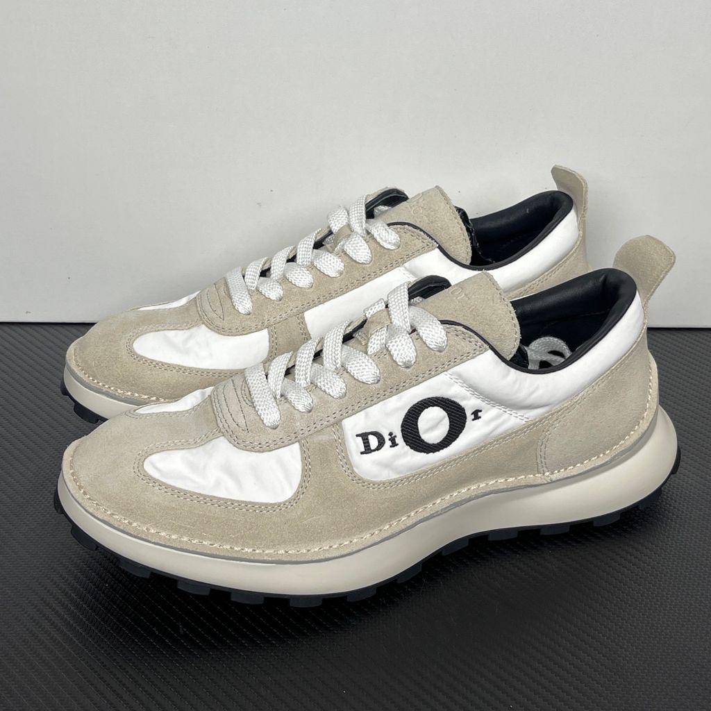 Side profile of the Dior Squash Sneaker, showcasing the white nylon base, beige suede overlays, prominent black "DiOr" side logo, and chunky white midsole with a black lugged outsole.