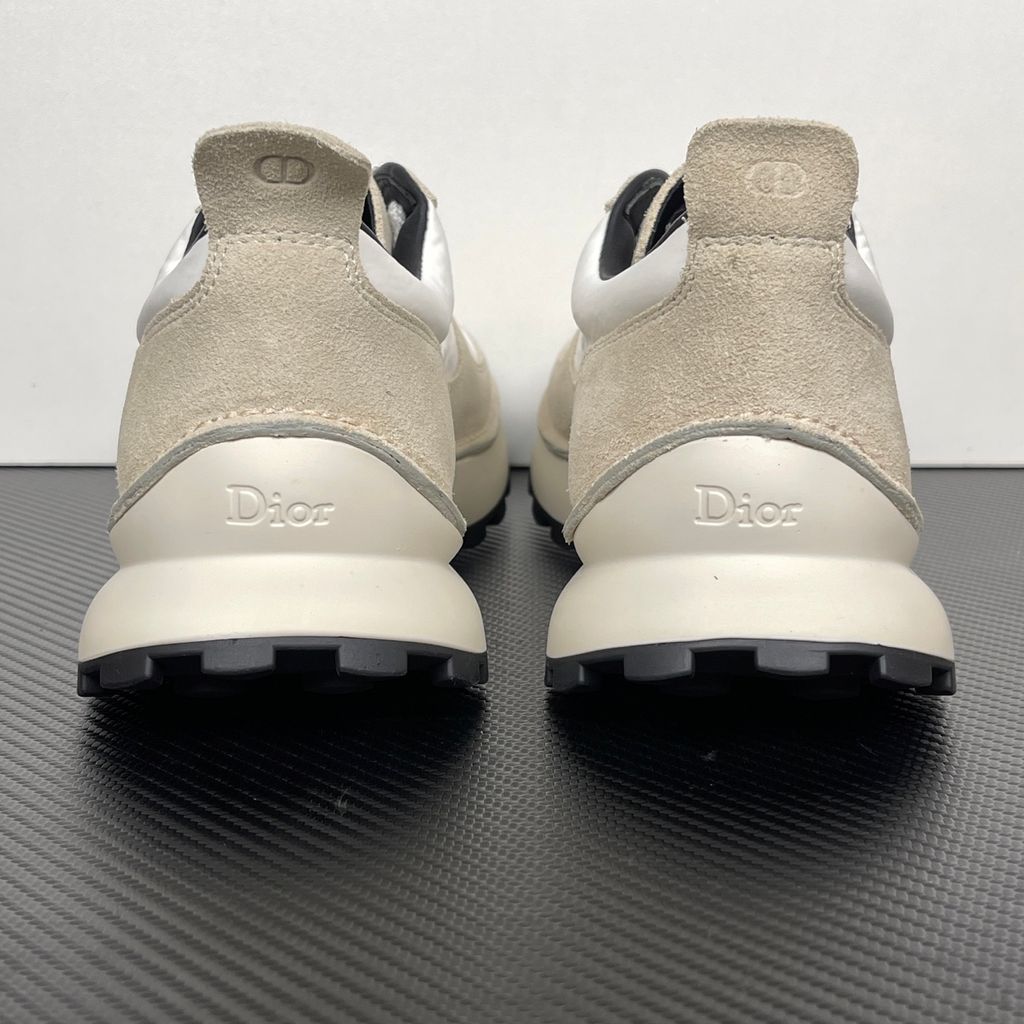 Side profile of the Dior Squash Sneaker, showcasing the white nylon base, beige suede overlays, prominent black "DiOr" side logo, and chunky white midsole with a black lugged outsole.