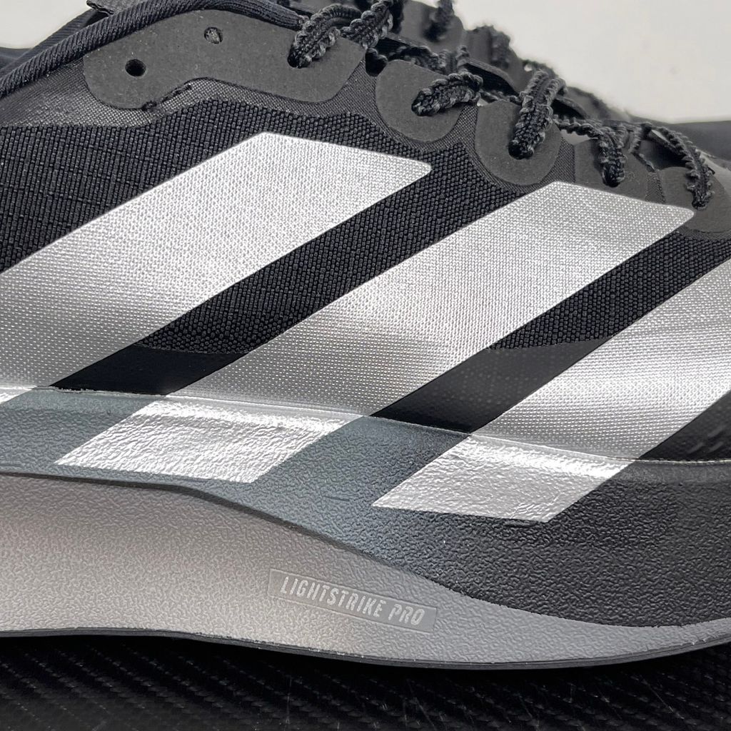 Side profile of the adidas Adizero Evo SL running shoe in the 'ATROnix Grey Black' colorway, showcasing the ultra-lightweight breathable mesh upper, sleek aerodynamic profile, and the sculpted Lightstrike Pro foam midsole.