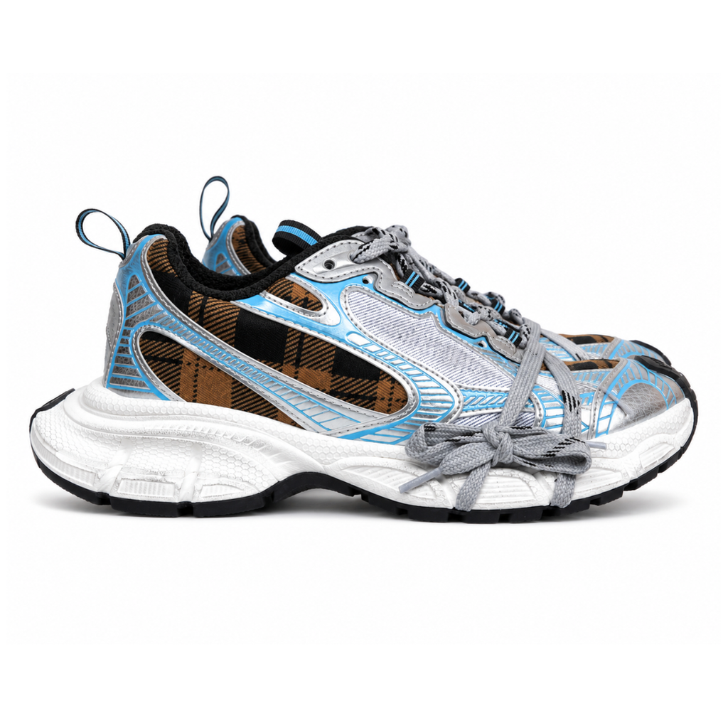 Side profile of the Balenciaga 3XL Sneaker showcasing a brown and black check pattern base, metallic silver overlays, light blue piping, a chunky distressed white sole, and the signature extra laces wrapped around the toe box.
