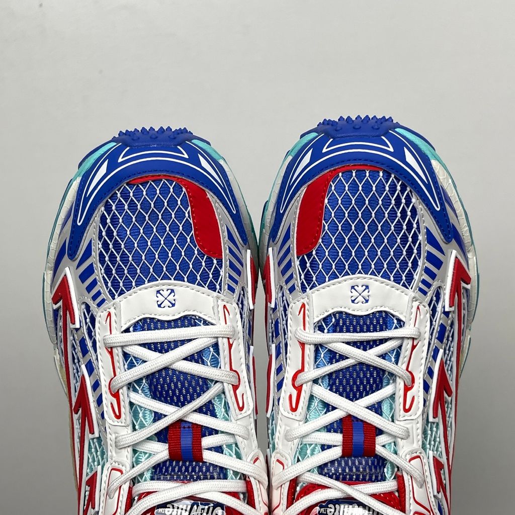 Side profile of the Off-White c/o Virgil Abloh sneaker showcasing a light blue mesh base, bold blue and red synthetic overlays, a large red arrow logo on the lateral side, and an attached blue and red zip-tie.